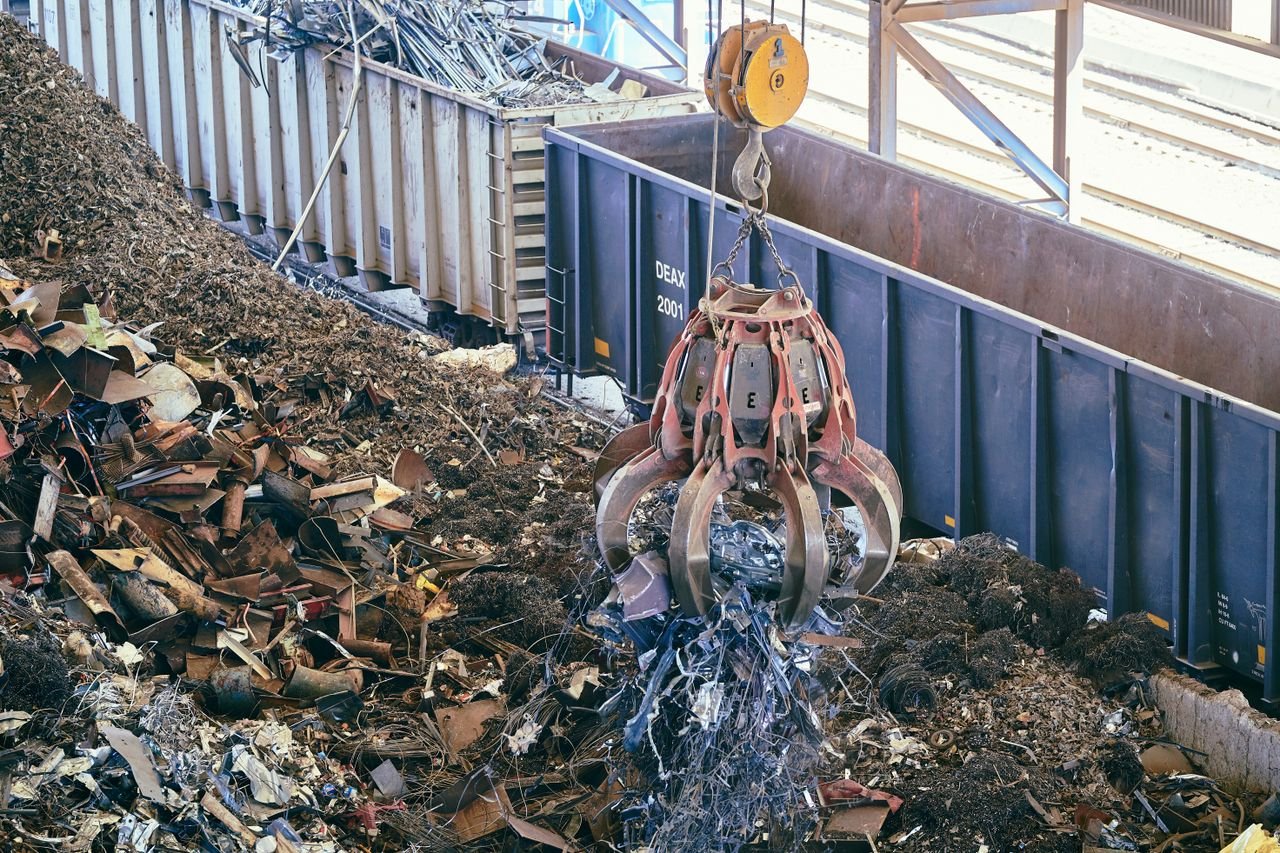brand-03 A claw crane lifting scrap metal in an industrial recycling facility.