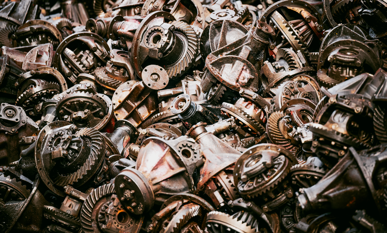 A dense pile of rusty mechanical gears and parts, creating an industrial texture.